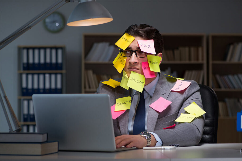 Túlterhelt irodai dolgozó színes cetlikkel az arcán, a stressz és mentális terhelés jelképeként.