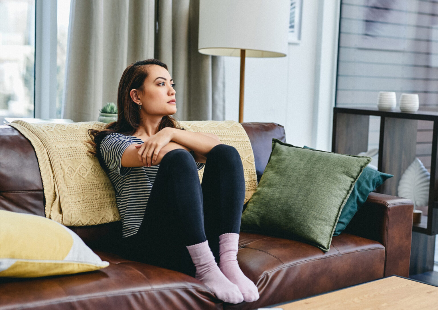 túlgondolás miatti belső feszültség, kanapén ülő nő bezárkózó testtartásban
